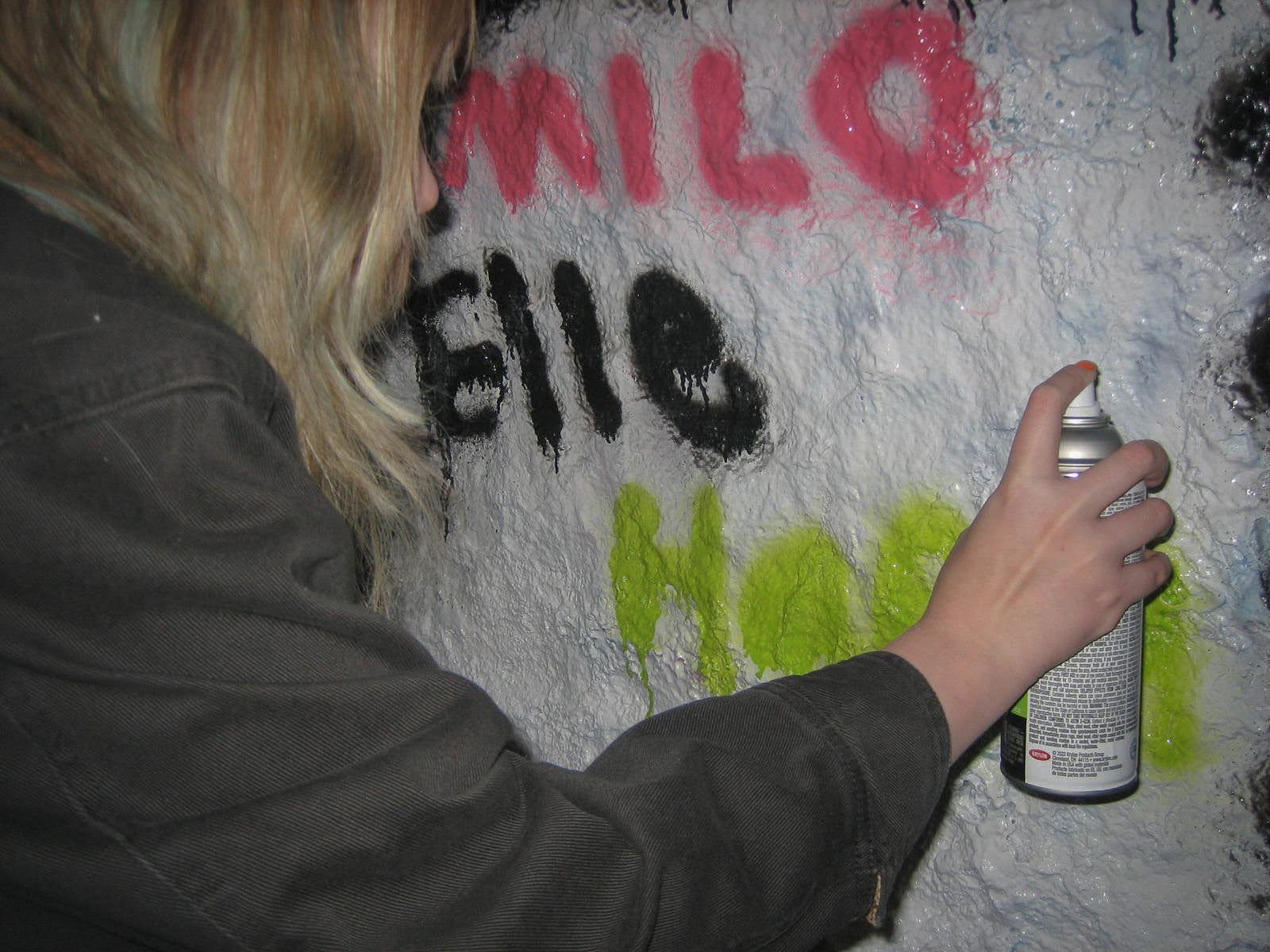 Woman spray painting graffiti.