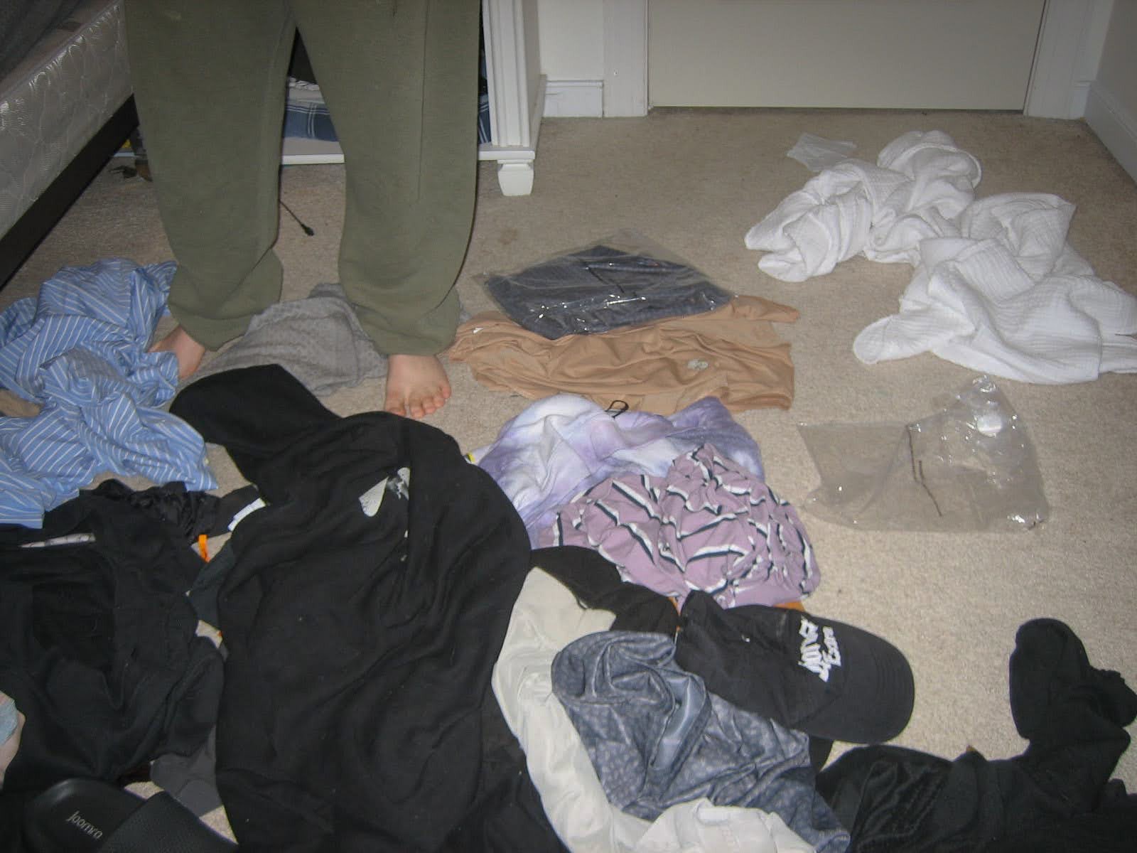 Bare feet standing on a messy bedroom floor. 